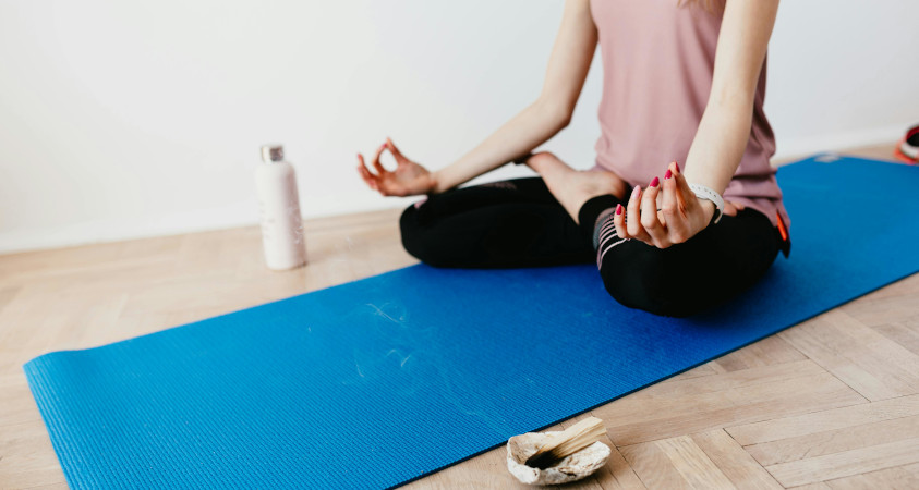 Frau sitzt auf Yogamatte und meditiert